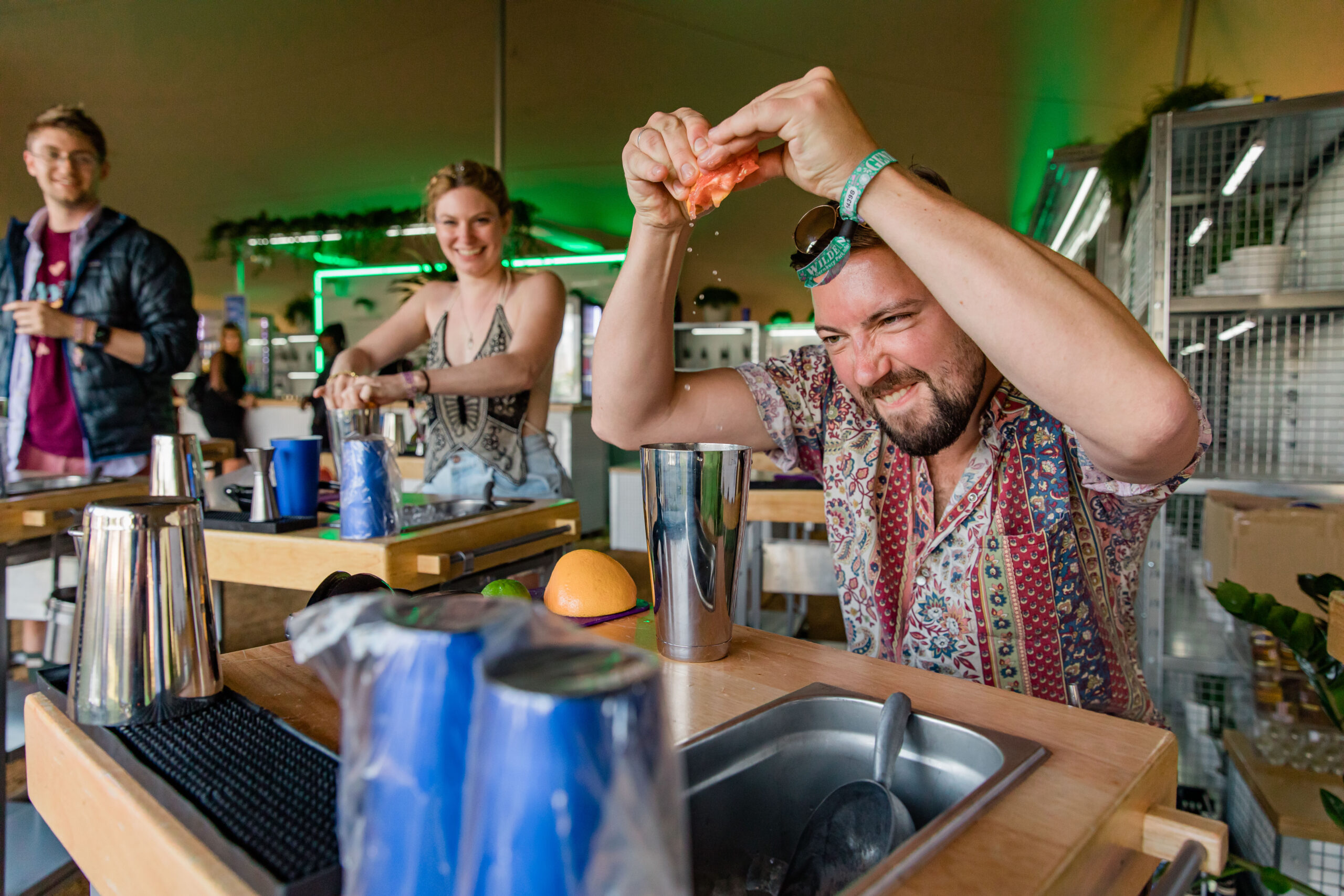 A man stood at a cocktail station in the Lab Bar activation at Wilderness Festival 2021 concreates as he squeezes a grapefruit into a cocktail shaker tin
