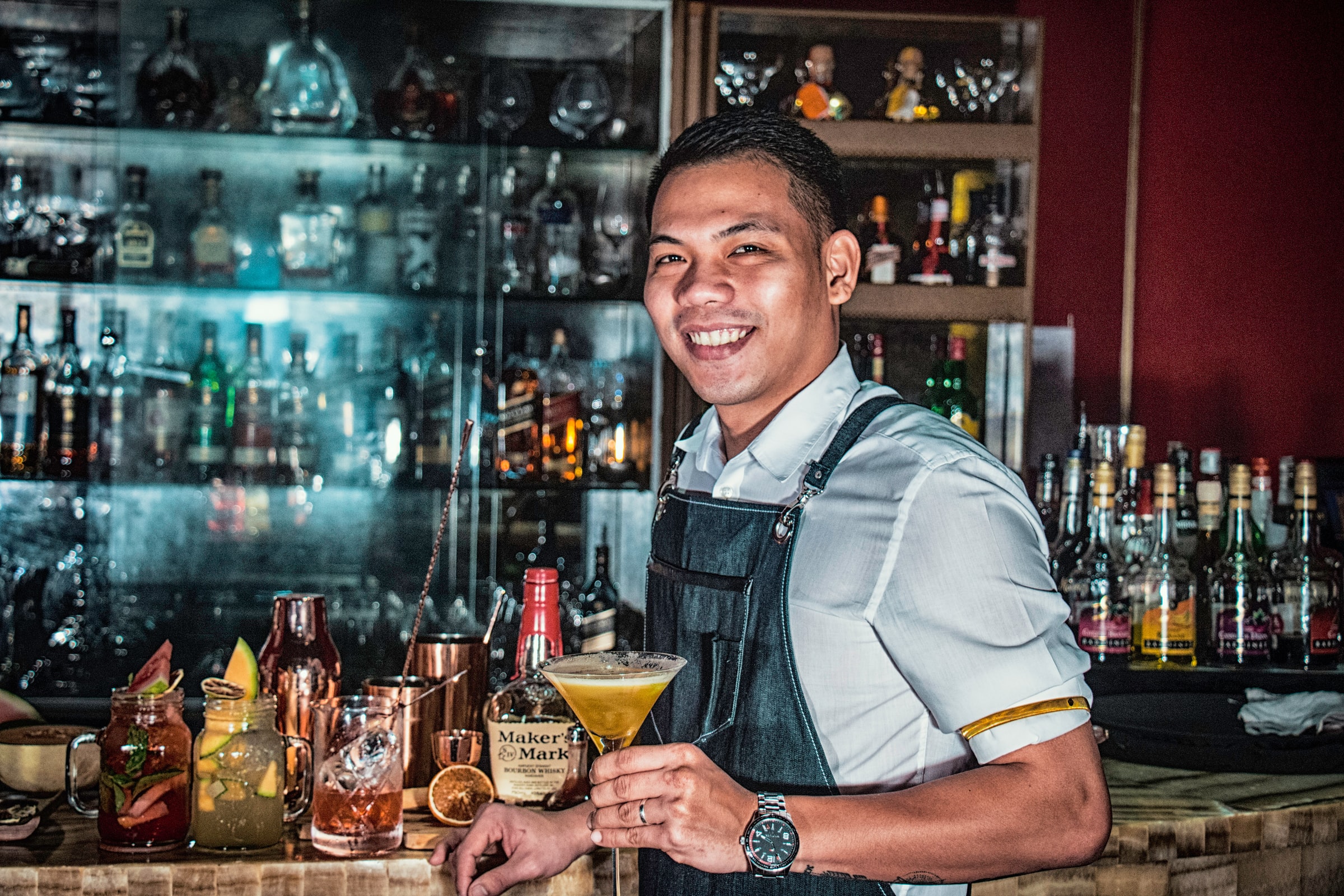 A bartender smiles, showing one of the most important factors when hiring a bartender: a friendly personality!