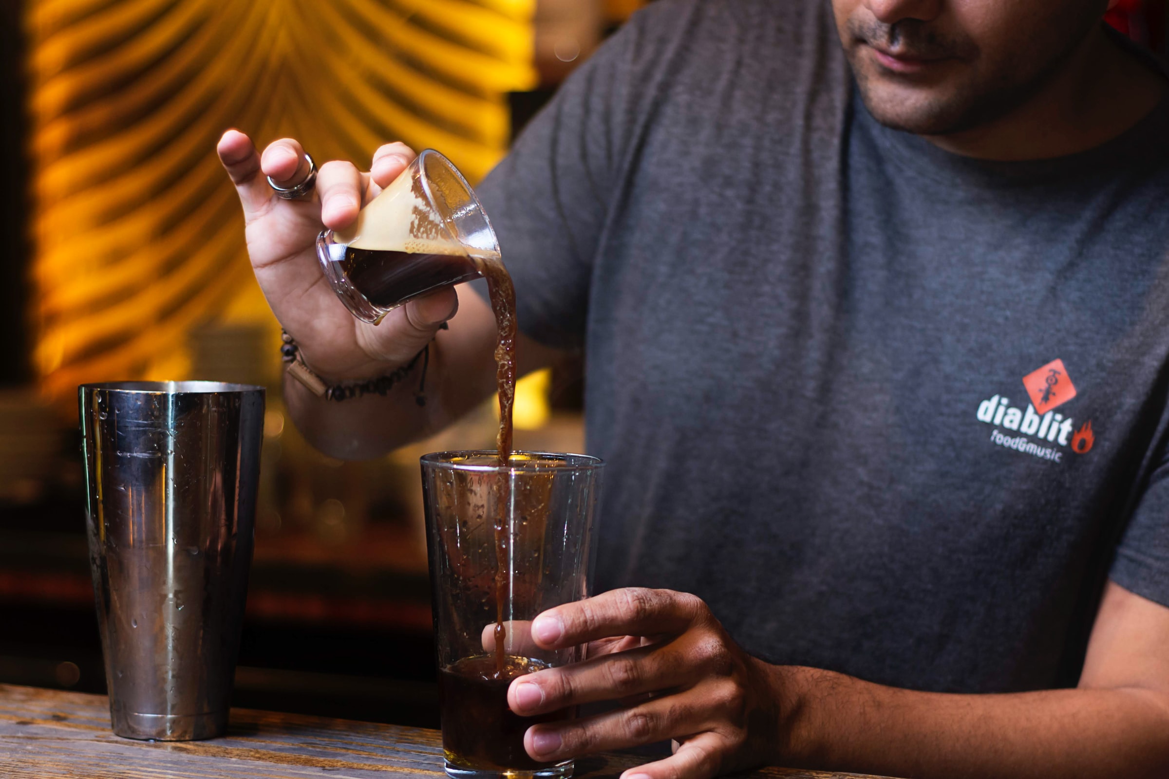 A bartender pours coffee liqueur into a glass