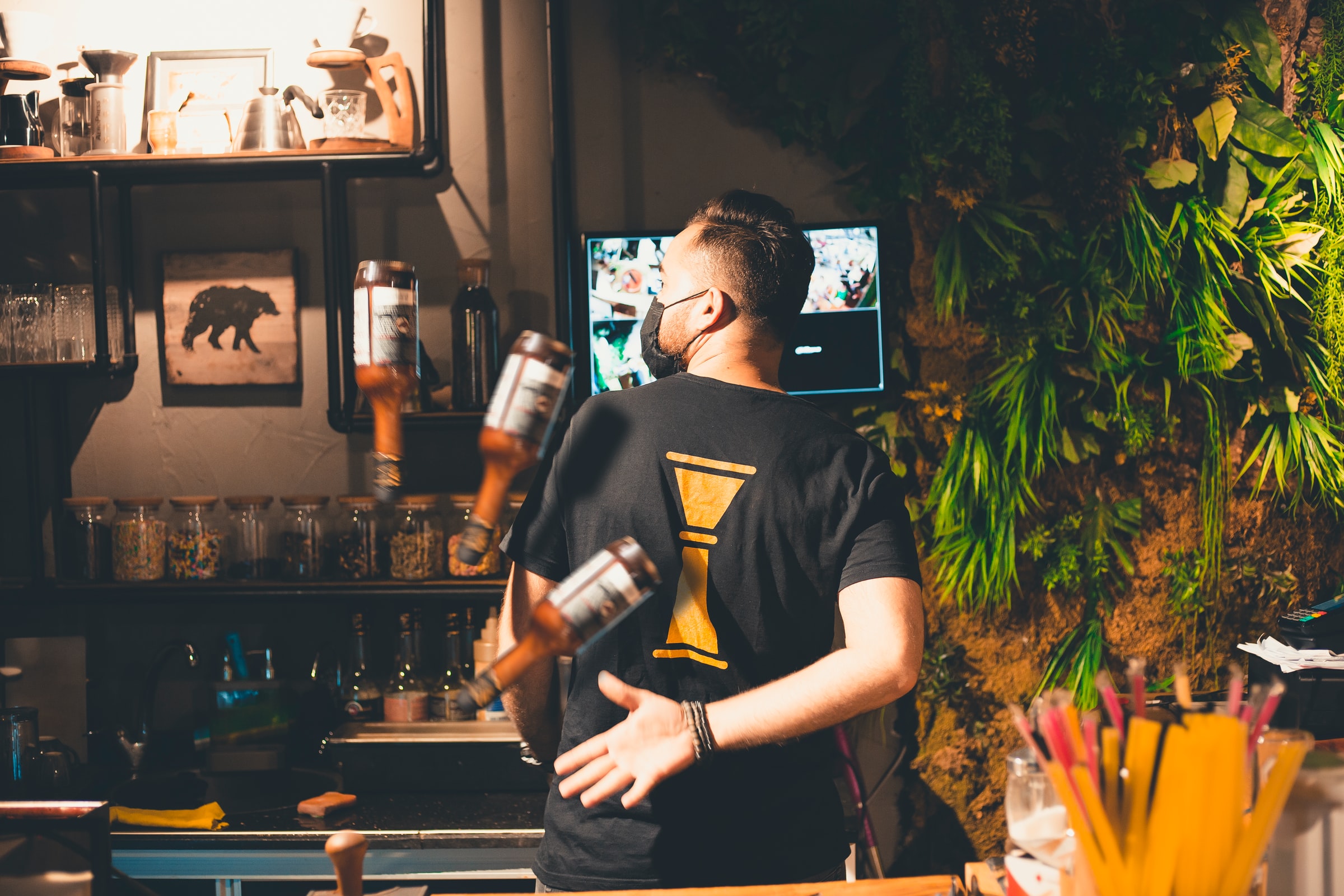 A flair bartender juggles spirit bottles behind his back