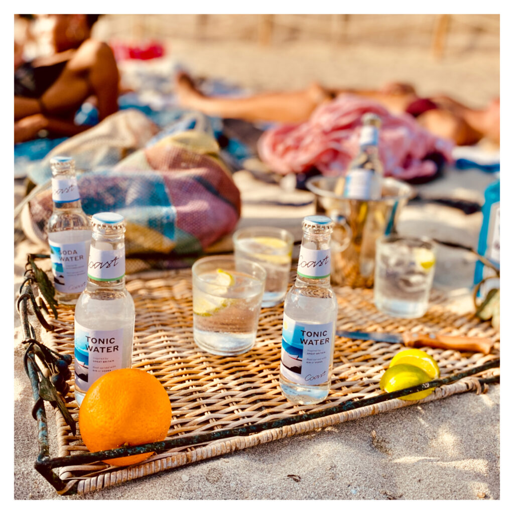 COAST Drinks tonic bottles on a beach towel